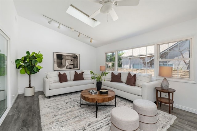 living area featuring a ceiling fan, wood finished floors, lofted ceiling with skylight, rail lighting, and baseboards