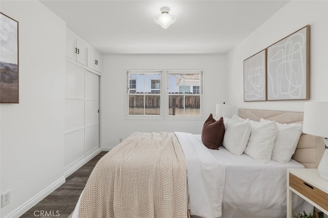 bedroom featuring baseboards, a closet, and dark wood-style floors