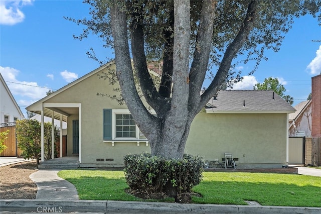 view of front of property featuring stucco siding, a front lawn, and fence