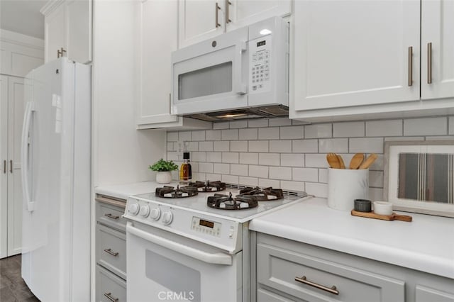kitchen with decorative backsplash, white appliances, light countertops, white cabinets, and dark wood-style floors
