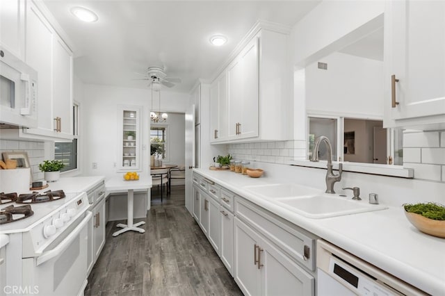 kitchen featuring white cabinets, white appliances, decorative backsplash, and a sink