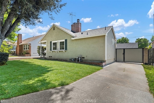 back of property with a chimney, concrete driveway, fence, a yard, and stucco siding
