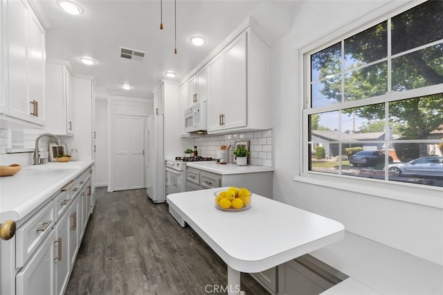 kitchen with a sink, white appliances, light countertops, visible vents, and recessed lighting