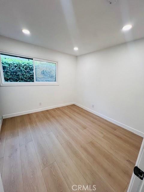 spare room with baseboards, light wood-type flooring, and recessed lighting