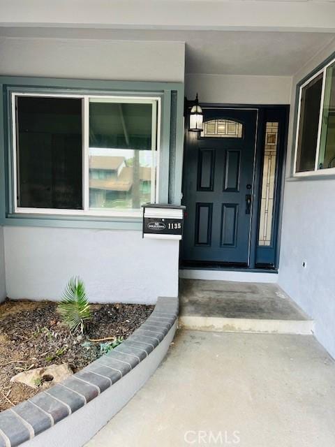 entrance to property featuring a porch and stucco siding