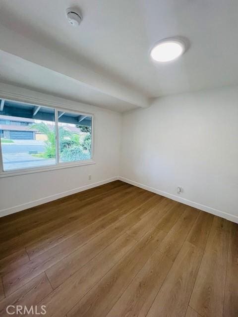 spare room featuring hardwood / wood-style floors and baseboards