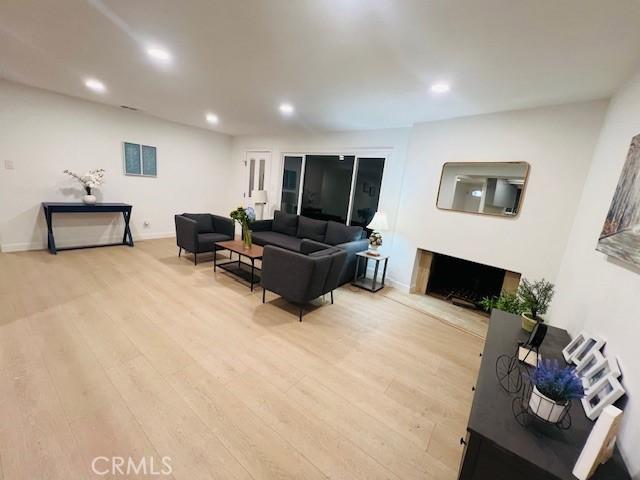 living area featuring baseboards, recessed lighting, light wood-style floors, and a fireplace