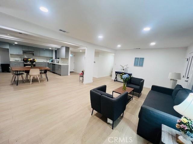 living area with baseboards, visible vents, light wood-type flooring, and recessed lighting