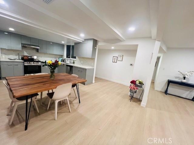 dining area featuring baseboards, recessed lighting, beam ceiling, and light wood finished floors