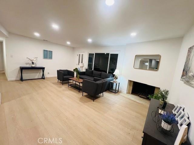 living area featuring baseboards, light wood-type flooring, a fireplace, and recessed lighting
