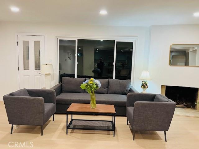 living area with recessed lighting, light wood-style flooring, and a fireplace