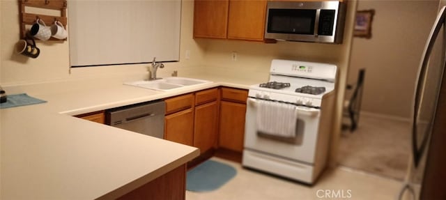 kitchen with brown cabinets, stainless steel appliances, light countertops, and a sink