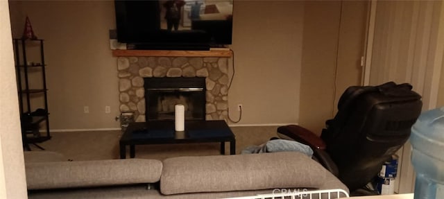 carpeted living area with a stone fireplace and baseboards