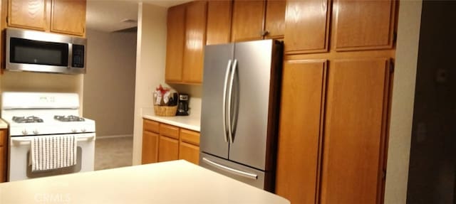 kitchen featuring light countertops, appliances with stainless steel finishes, and brown cabinets