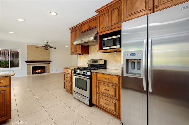 kitchen with stainless steel appliances, under cabinet range hood, ceiling fan, decorative backsplash, and light tile patterned flooring