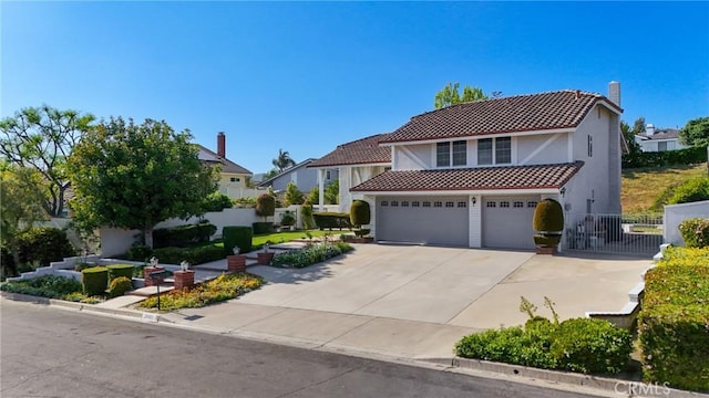 mediterranean / spanish-style house featuring a tiled roof, concrete driveway, stucco siding, and a chimney