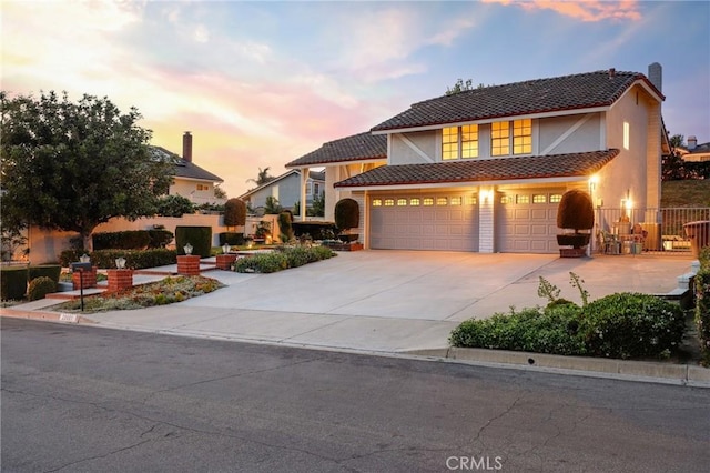 traditional home featuring stucco siding, a garage, and driveway