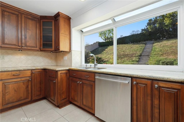 kitchen featuring stainless steel dishwasher, a sink, light tile patterned floors, and decorative backsplash