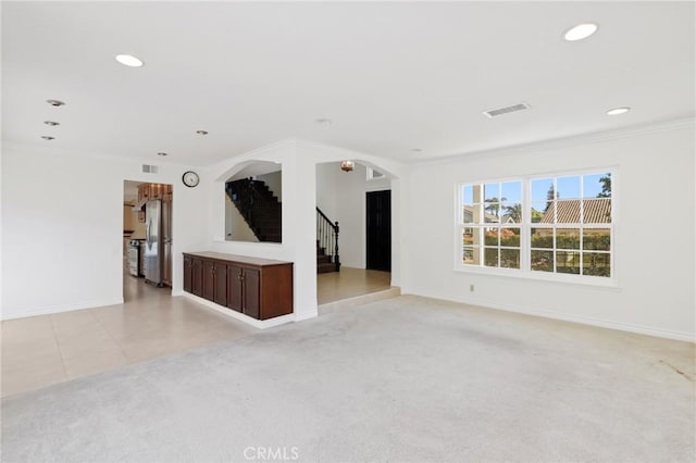 unfurnished living room featuring arched walkways, stairway, baseboards, recessed lighting, and light carpet