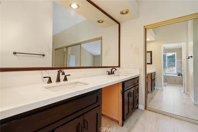 full bathroom with double vanity, baseboards, marble look tile flooring, a tub to relax in, and recessed lighting