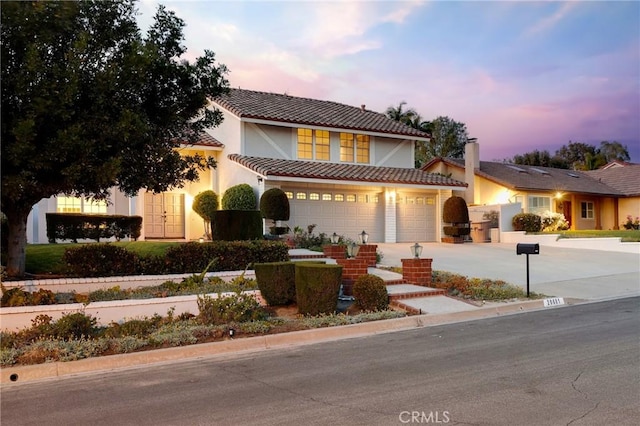 mediterranean / spanish house featuring concrete driveway, stucco siding, a tiled roof, and an attached garage