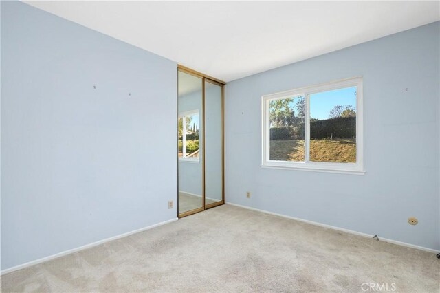unfurnished room featuring light carpet and baseboards