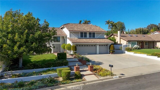 mediterranean / spanish-style house featuring driveway, a tiled roof, stucco siding, an attached garage, and a front yard