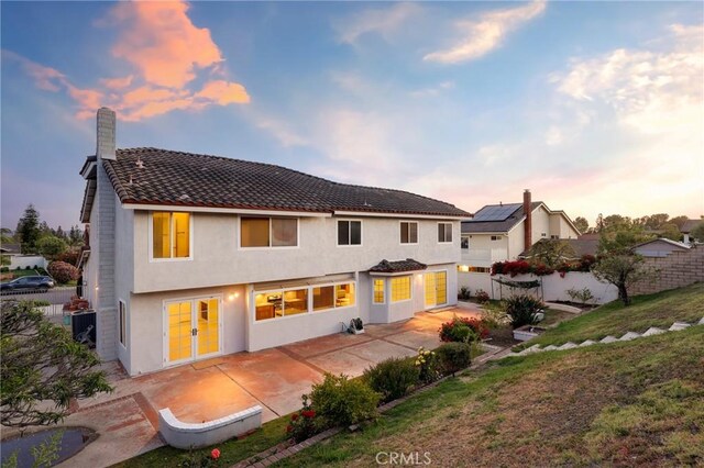 rear view of house featuring a patio, stucco siding, and a tiled roof