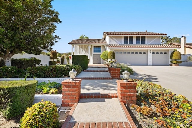 view of front facade with driveway, stucco siding, a tiled roof, and an attached garage