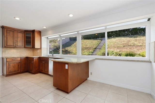 kitchen featuring a peninsula, a sink, glass insert cabinets, tasteful backsplash, and stainless steel dishwasher