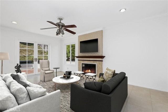 living area with french doors, ceiling fan, crown molding, a large fireplace, and light tile patterned floors