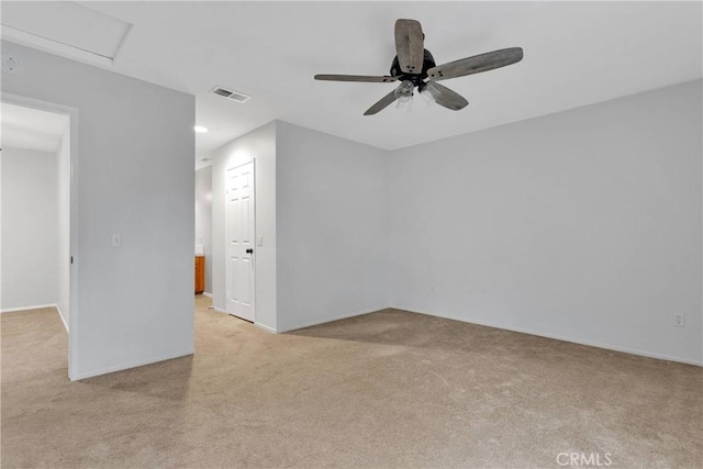 empty room with ceiling fan, visible vents, baseboards, and light carpet