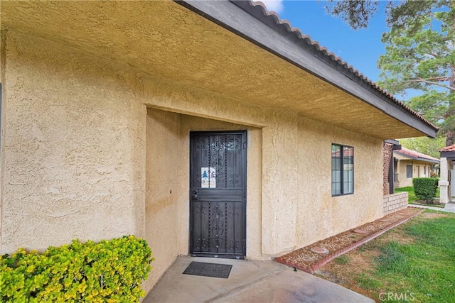 property entrance featuring a tile roof and stucco siding