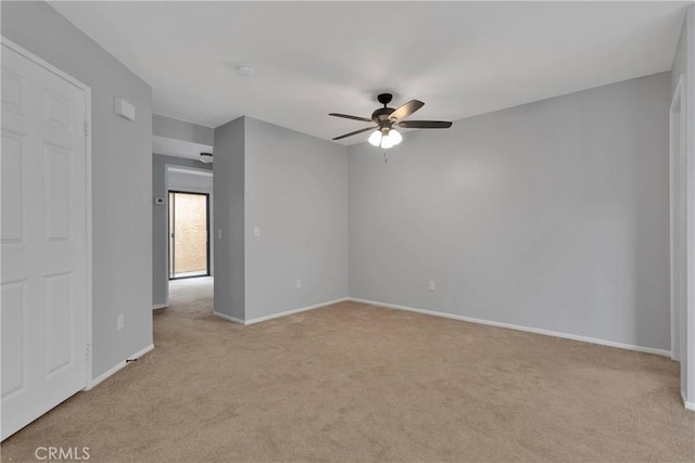 empty room with light carpet, a ceiling fan, and baseboards