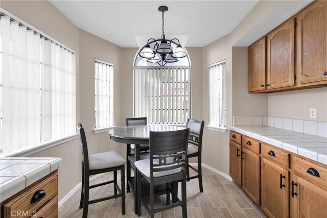 dining area with baseboards, light wood-style floors, and a notable chandelier