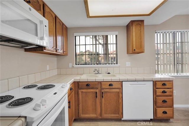 kitchen featuring white appliances, a sink, and brown cabinets