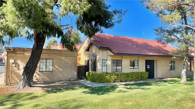 view of front of house with stucco siding, a tile roof, and a front yard