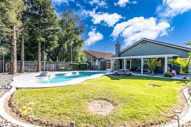 view of pool featuring a fenced backyard, a shed, a patio area, an outbuilding, and a lawn