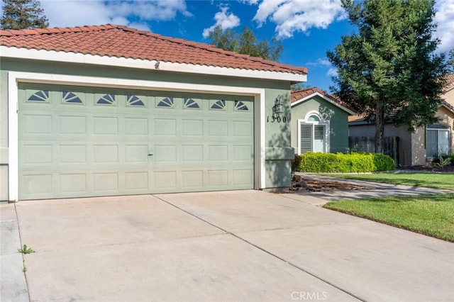 mediterranean / spanish home featuring an attached garage, a tiled roof, stucco siding, and concrete driveway