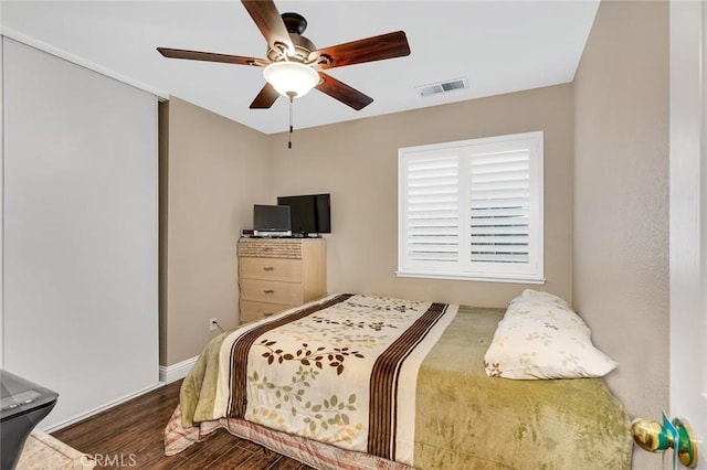 bedroom featuring ceiling fan, visible vents, baseboards, and dark wood-style flooring