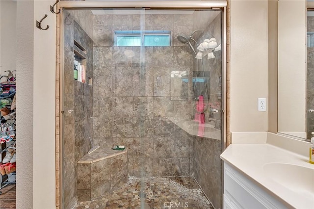 bathroom with a textured wall, vanity, and a stall shower