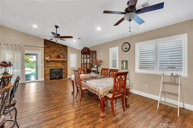 dining room featuring lofted ceiling, wood finished floors, visible vents, a stone fireplace, and ceiling fan