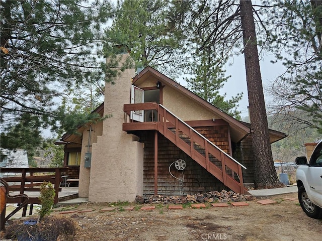 32868 Deer Ln, Running Springs, CA 92382 - view of front facade featuring stairs, a chimney, and stucco siding