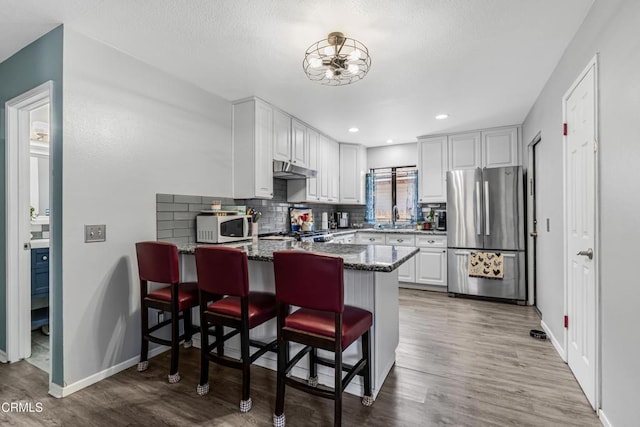 232 Prospect St, Oak View, CA 93022 - kitchen with freestanding refrigerator, white microwave, a peninsula, a sink, and dark stone countertops