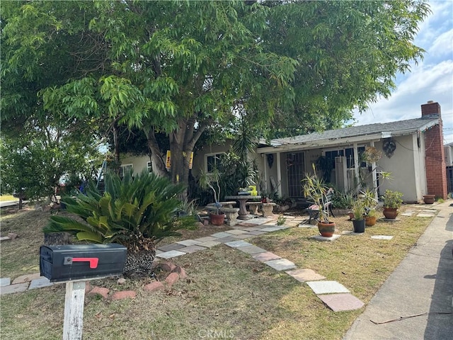 1017 N Alice Ave, Rialto, CA 92376 - view of front of home featuring stucco siding, a chimney, and a front lawn