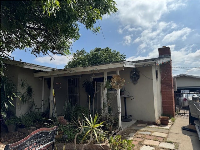 1017 N Alice Ave, Rialto, CA 92376 - view of property exterior with stucco siding, a chimney, and fence