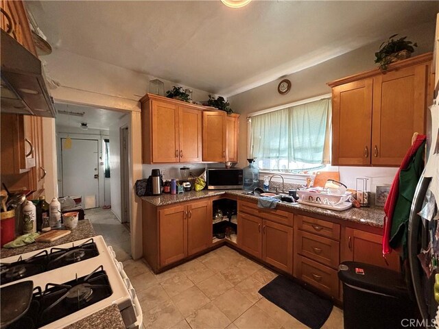 3852 4th St, Riverside, CA 92501 - kitchen featuring brown cabinetry, stainless steel microwave, white gas stove, and a sink