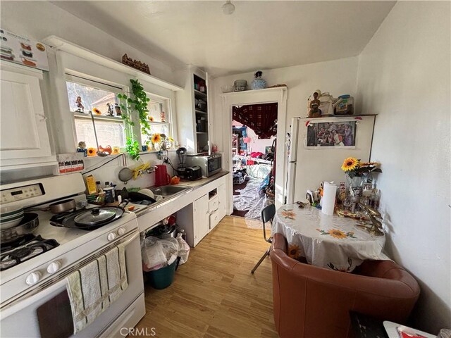 3852 4th St, Riverside, CA 92501 - kitchen featuring stainless steel microwave, light countertops, light wood-style flooring, and white range with gas cooktop