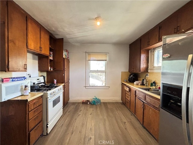 3852 4th St, Riverside, CA 92501 - kitchen featuring a sink, white appliances, light wood-type flooring, light countertops, and baseboards
