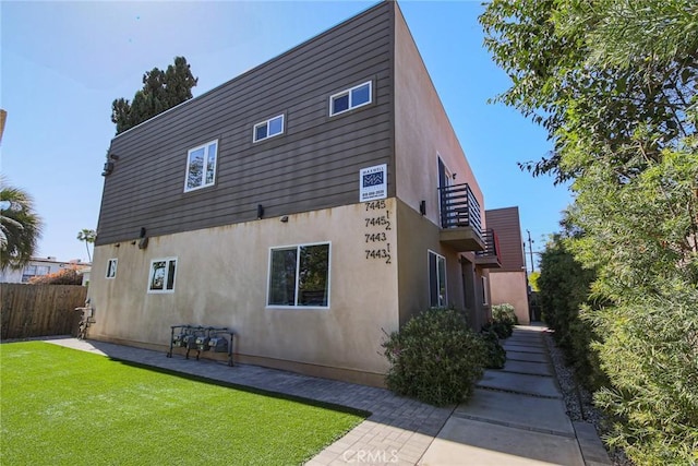 7443 Troost Ave, North Hollywood, CA 91605 - rear view of property featuring stucco siding, fence, and a yard